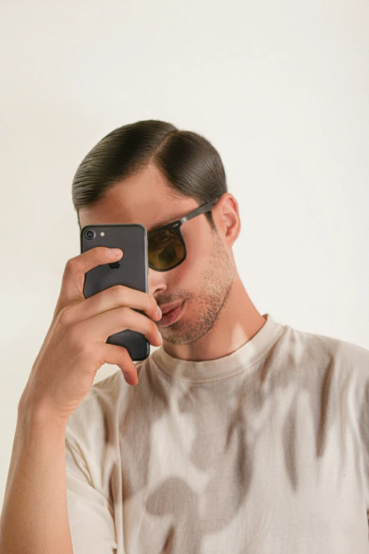 a man in sunglasses uses a cell phone to take a selfie
