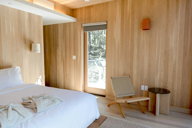 a bedroom has a chair, bed and wooden paneling