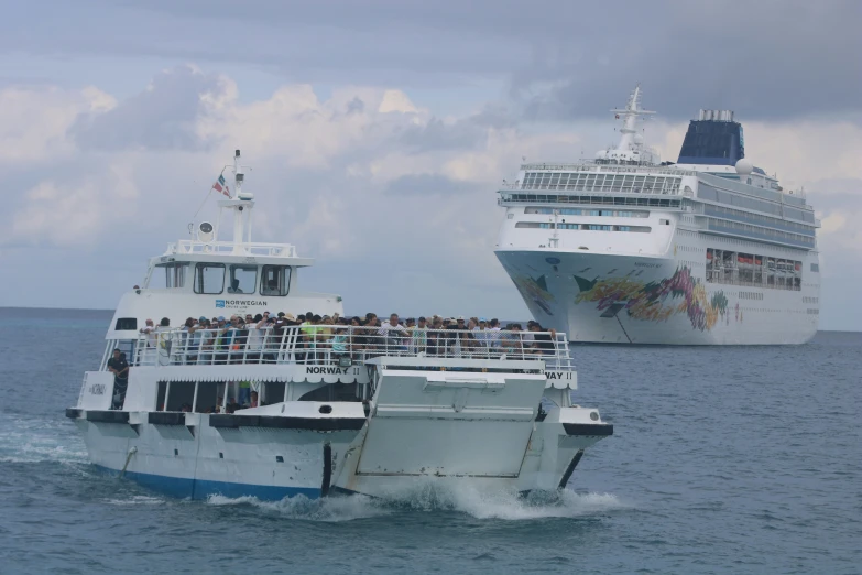 two large ships with passengers on top of them in the water