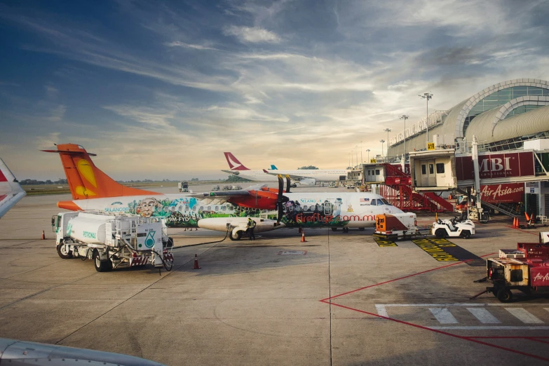 several airplanes parked in an airport with luggage cart parked on the side