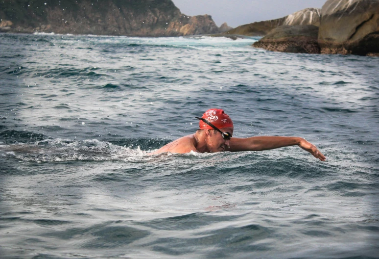 a person in a red swim cap swimming in the water