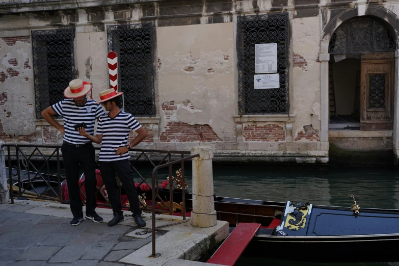 two people standing next to a boat in a river