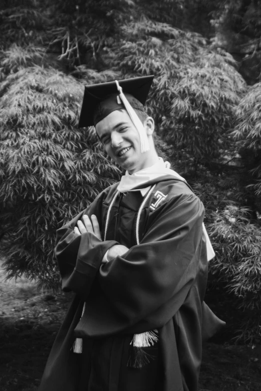 a woman with her arms crossed wearing a graduation hat