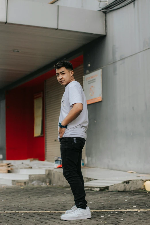 a man in grey t - shirt and black pants standing on sidewalk