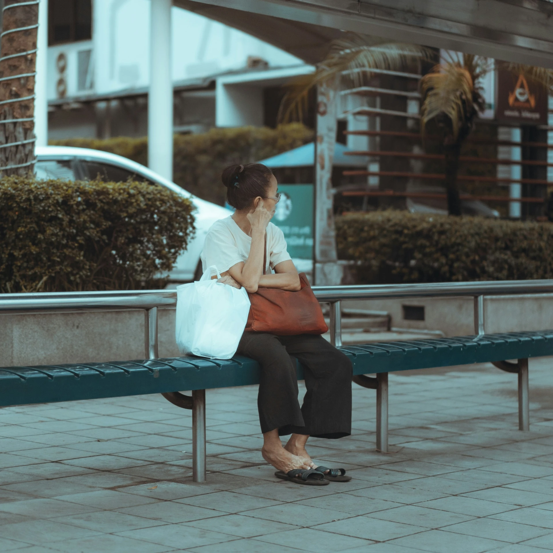 a woman on her cellphone sits on the bench