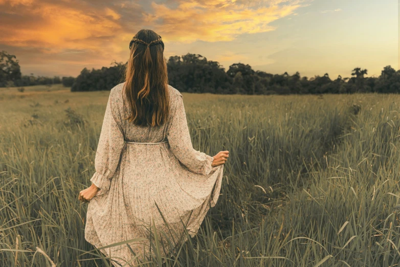 woman in long dress standing in tall grass