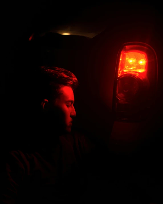 a man staring through a rear light of a car