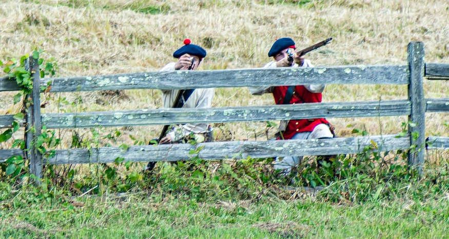 two people wearing red and white outfits standing by a fence