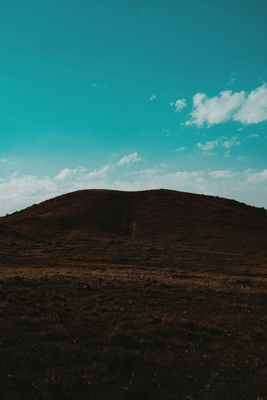 a large hill with a blue sky in the background