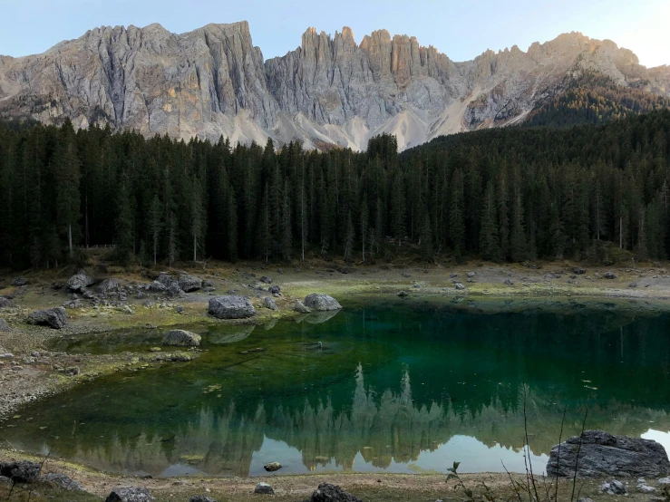 a mountain scene is reflected in the clear water of the lake