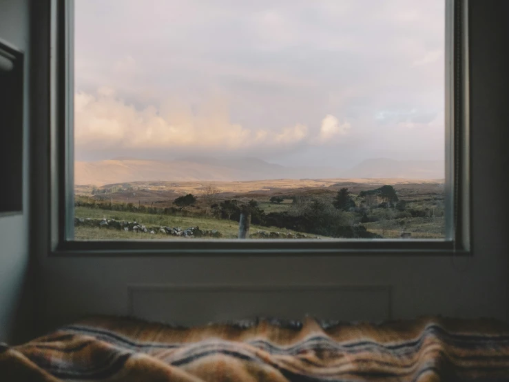 a bedroom with a bed, blanket and view of mountains