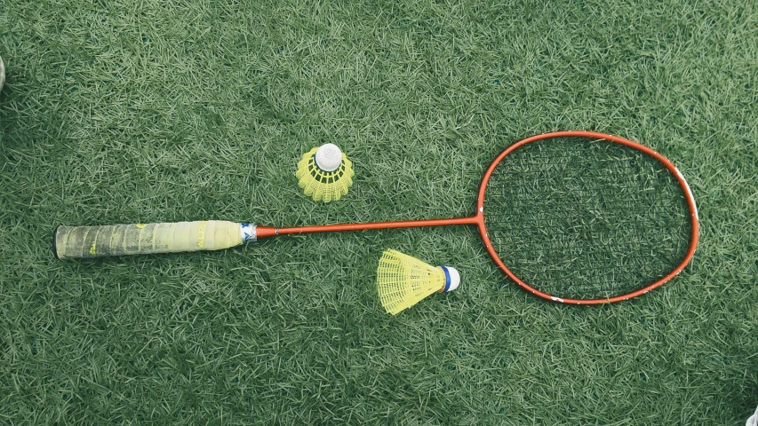 a badminton racket laying on the grass next to balls
