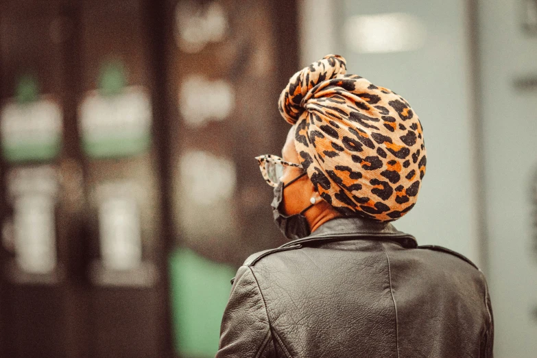 a woman in black jacket wearing a cheetah print head scarf