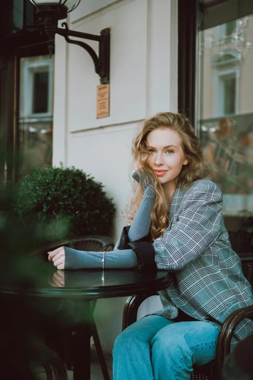 a woman is sitting at an outdoor table smiling