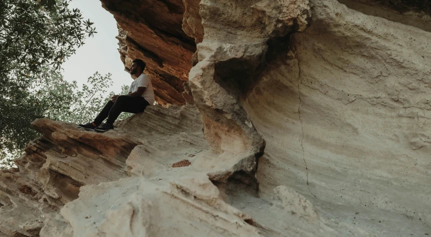 a man on a cliff looks down at the ground