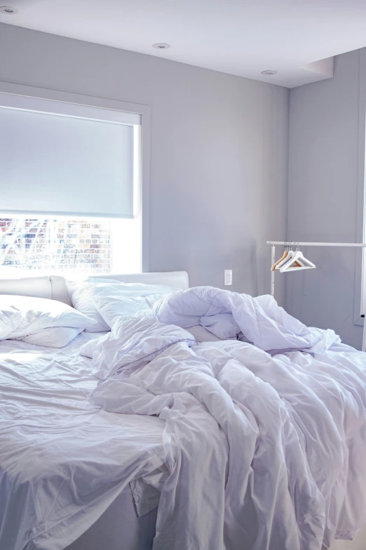 an unmade bed with lots of pillows in a room