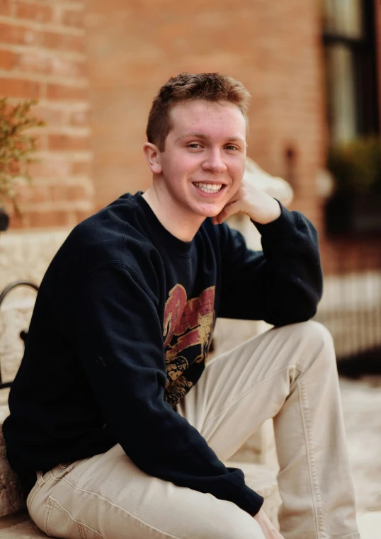 a young man sitting on a bench smiling