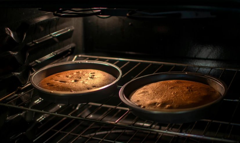 two cake pans sitting on top of an oven