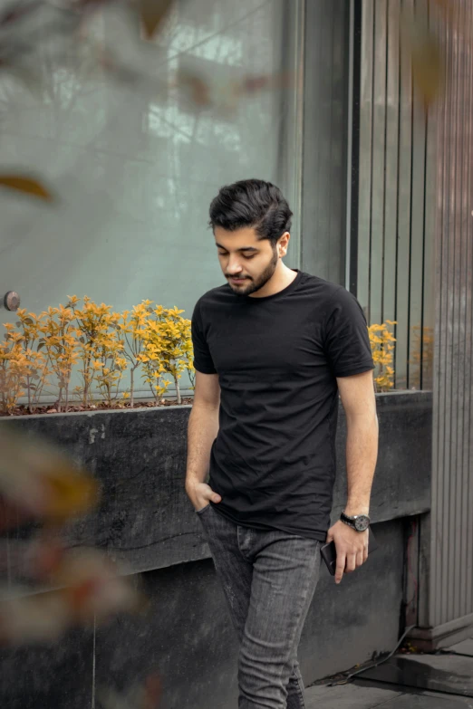 a young man wearing black standing near a flower box