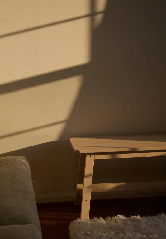 a wood bench in a corner with sunlight from the window