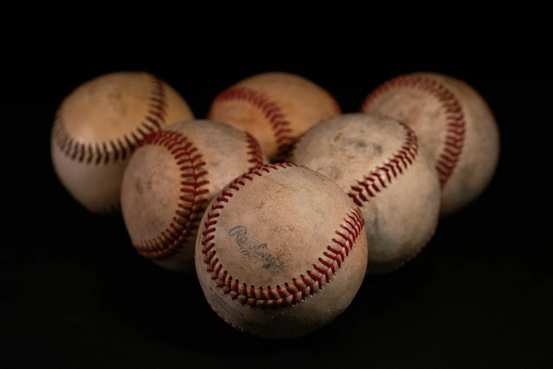 five baseballs stacked together on a black background