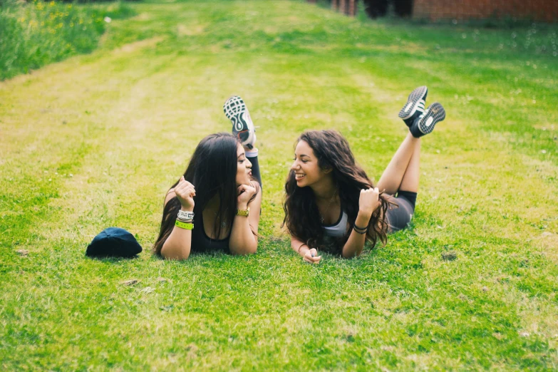 two girls laying on the grass holding their guitars