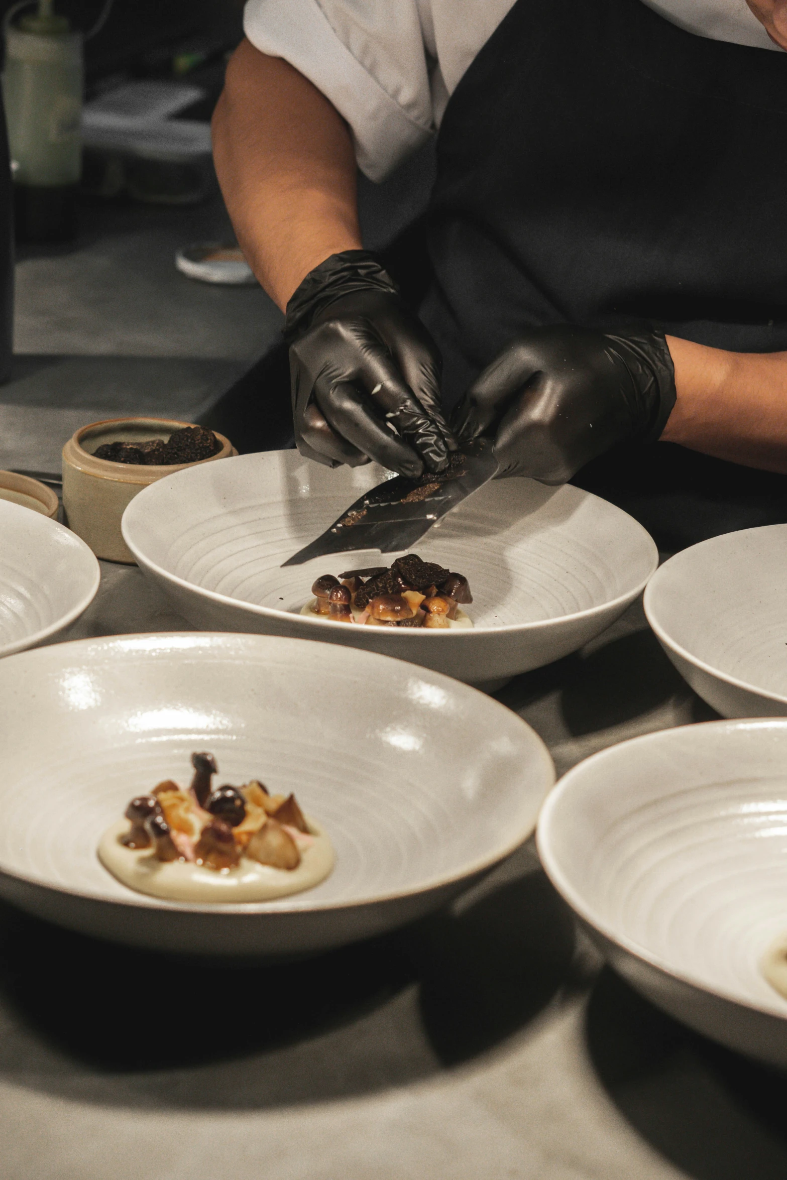 several plates and a person in black gloves  up food