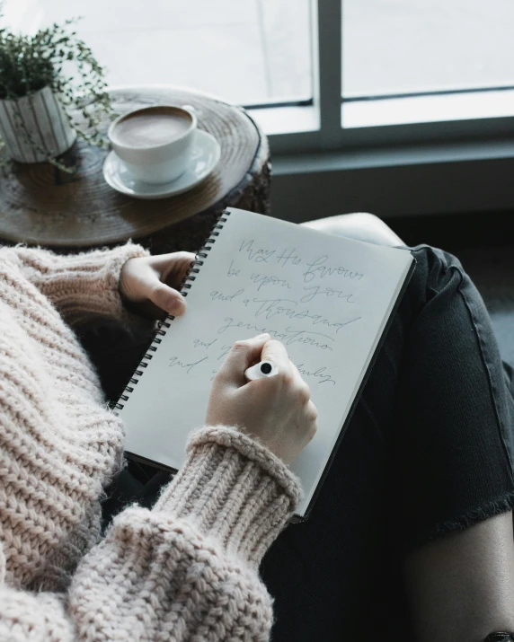 a person is sitting down writing in their notebook