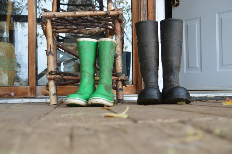 two pair of rain boots in front of a door