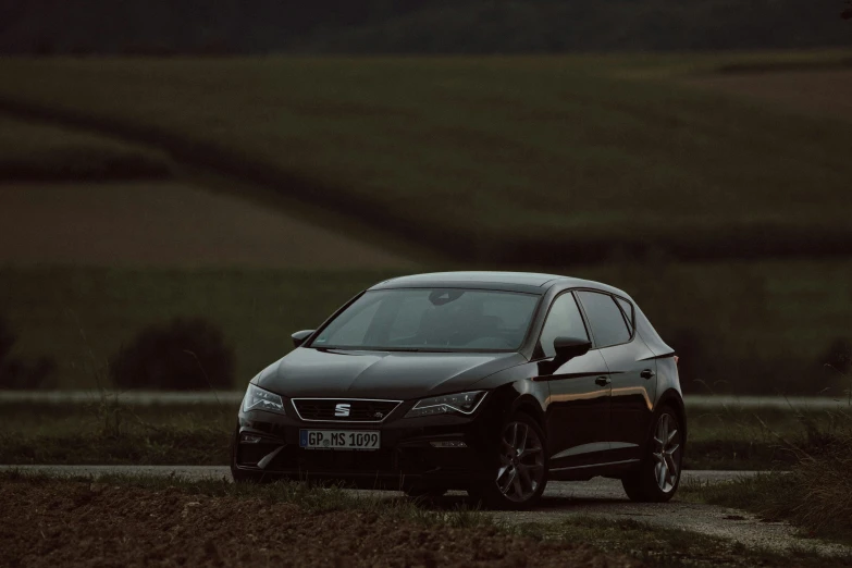 the dark car is driving along the rural road