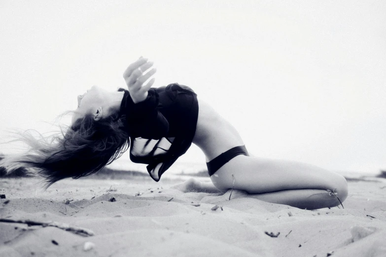 a woman lying down on the beach with her arms outstretched