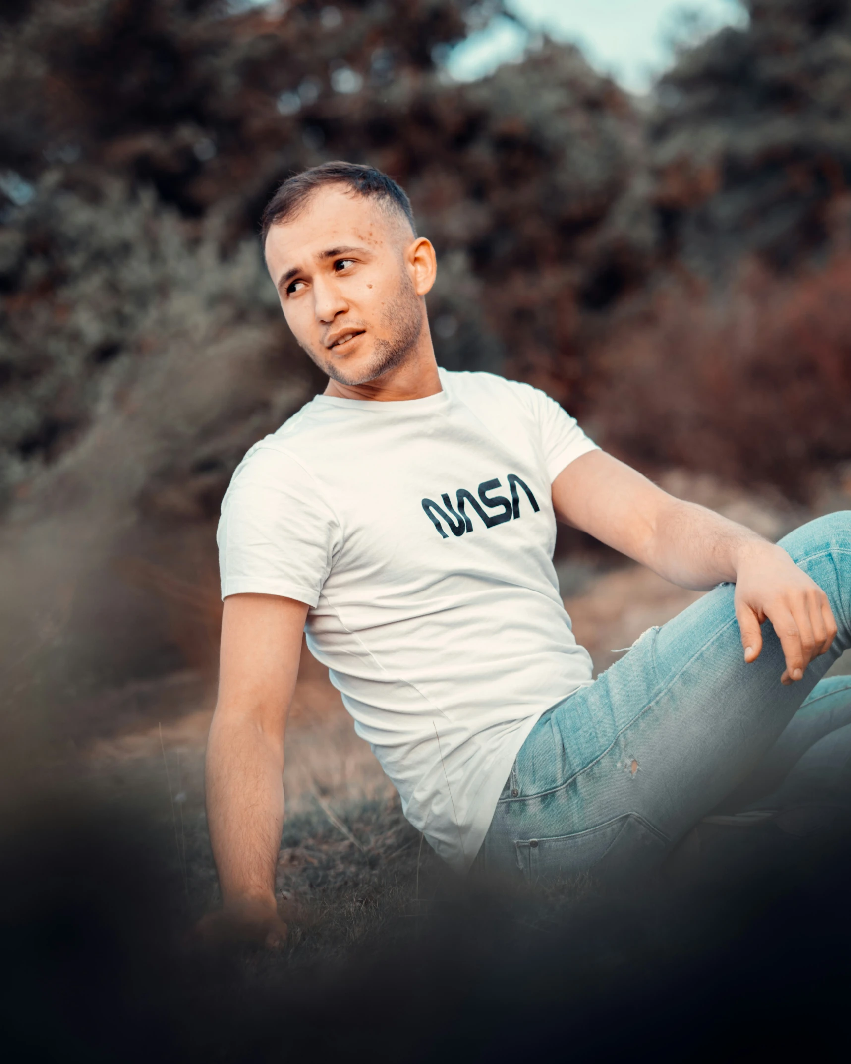 young man with bald head sitting on the ground posing