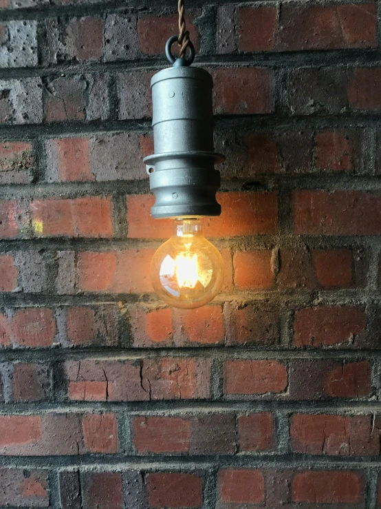 an old metal hanging light bulb on a brick wall