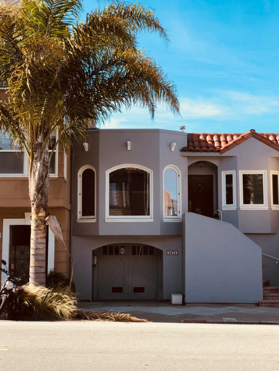 a gray house is shown in front of a tree