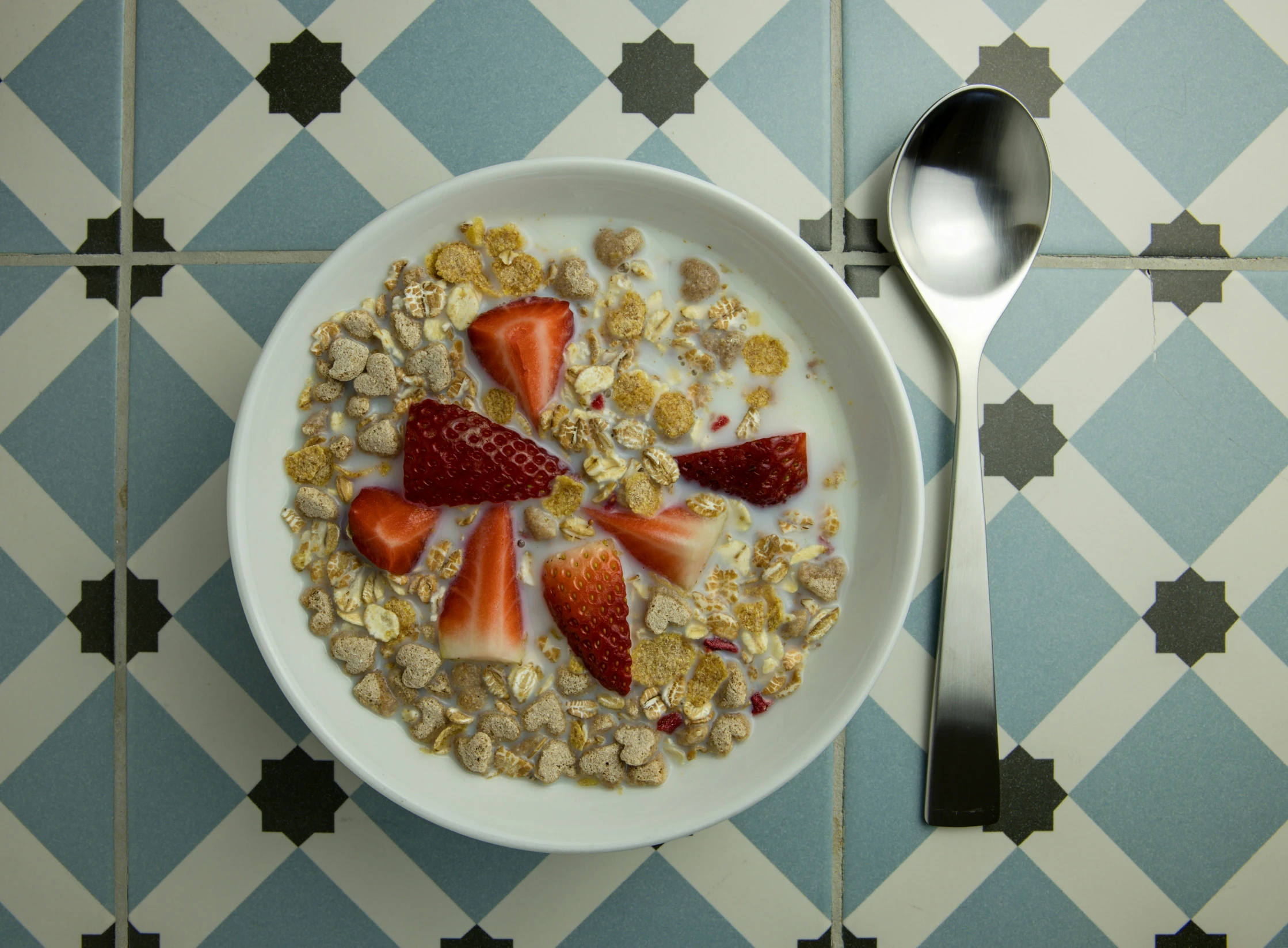 bowl filled with granola and strawberry slices and topped with syrup