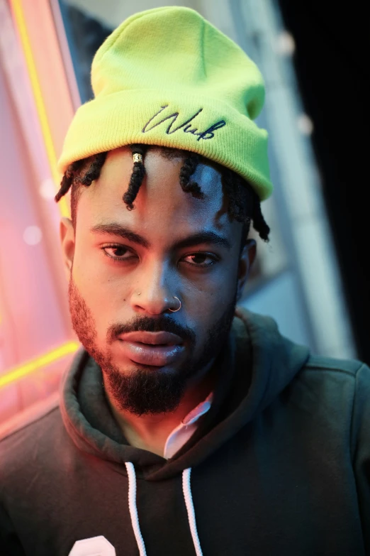 a man with dreadlocks on with a neon colored hat