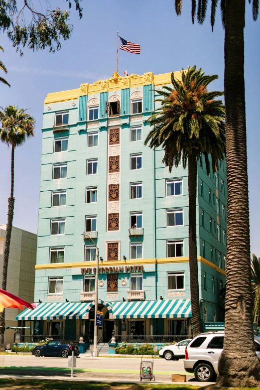 the buildings of a resort with palm trees and an umbrella on a sunny day