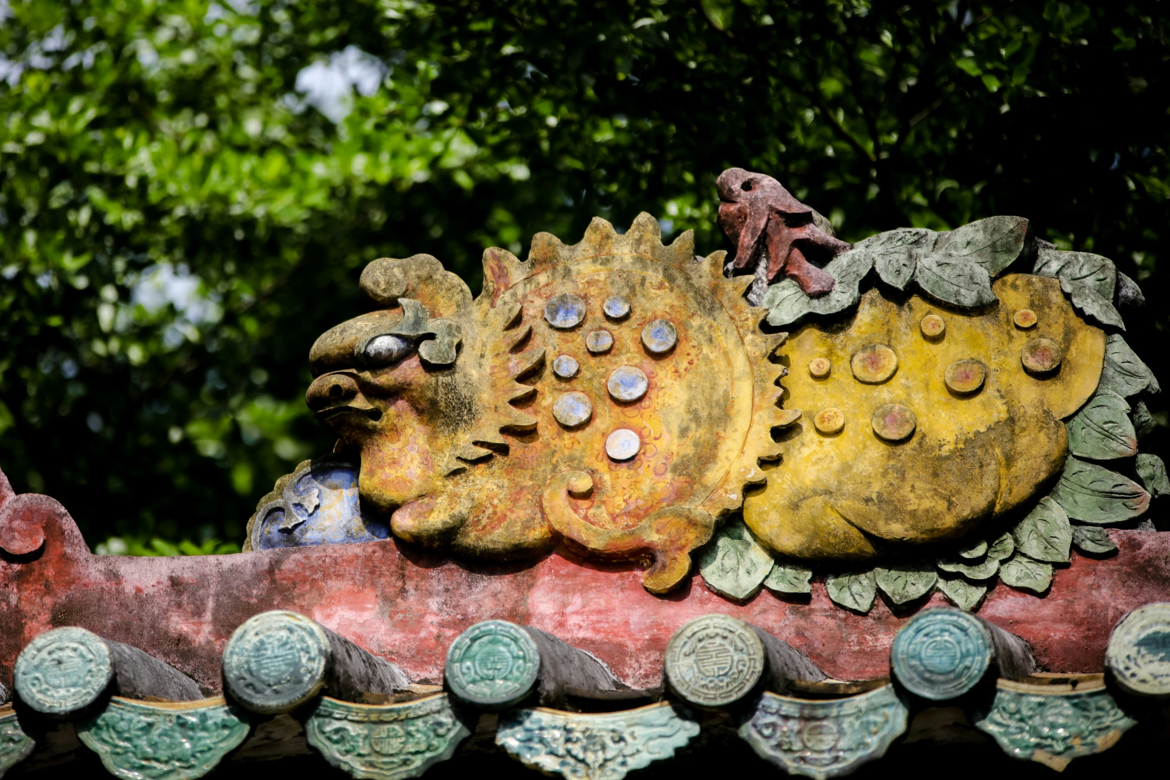 two colorful sculptures sitting on a red, stone structure