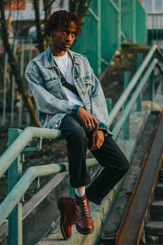 a black male sits with his feet on the rail outside of his house