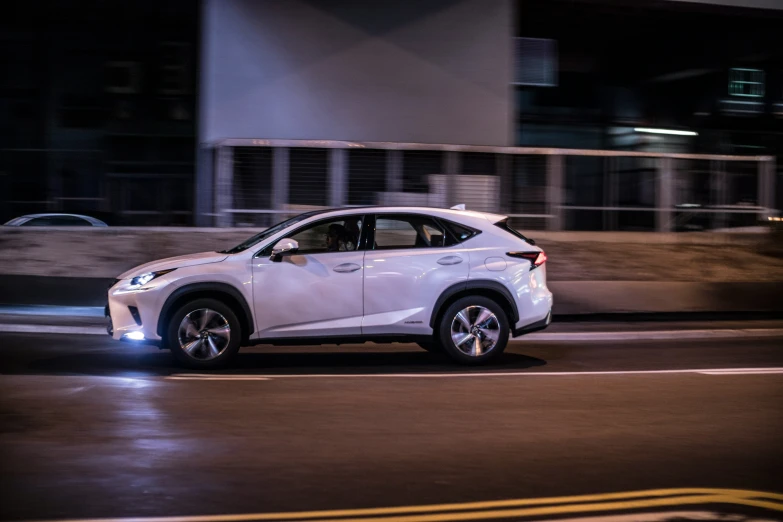 the white car is driving on a city street at night