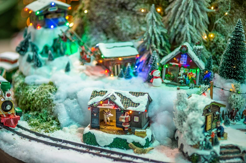 a holiday train engine on the tracks with many small christmas village