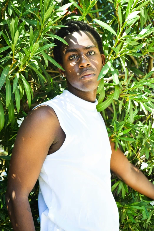 a young man standing in front of a tree