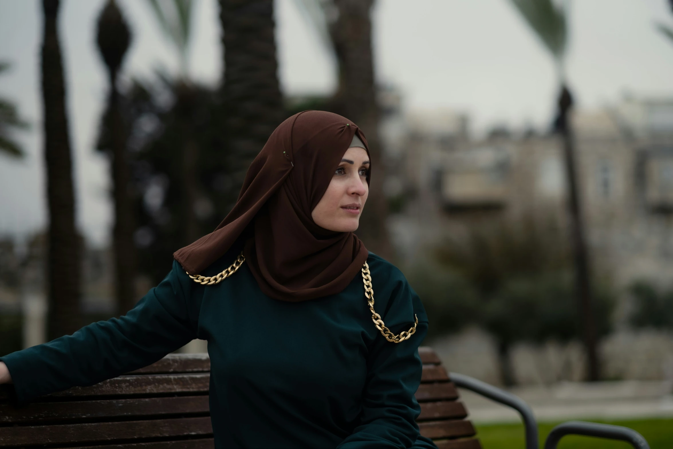 there is a woman sitting on a bench and wearing a headscarf