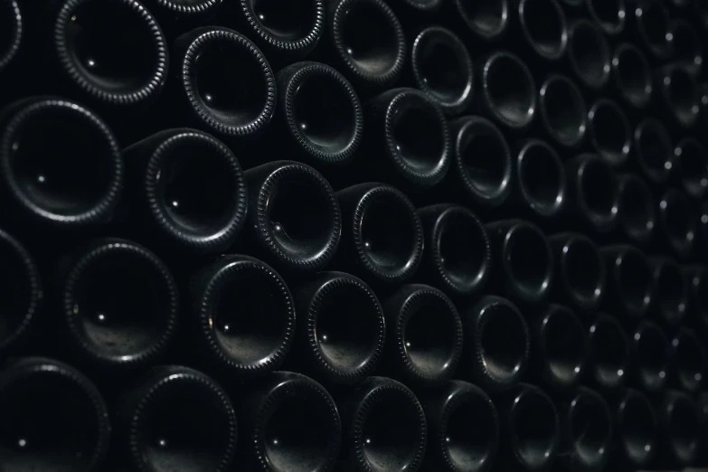 a wall filled with black empty wine bottles