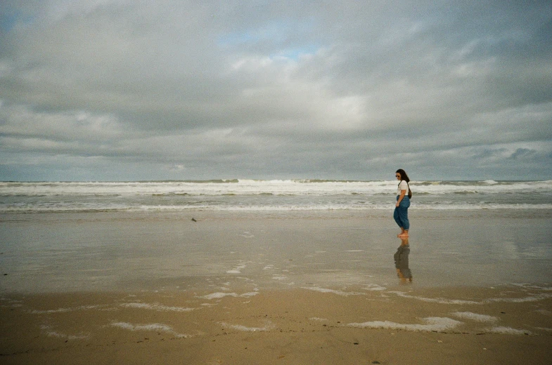 a woman walking along the beach during the day
