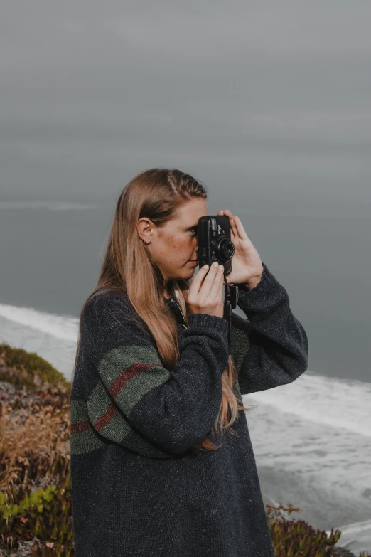 a woman with her camera taking a po by the water