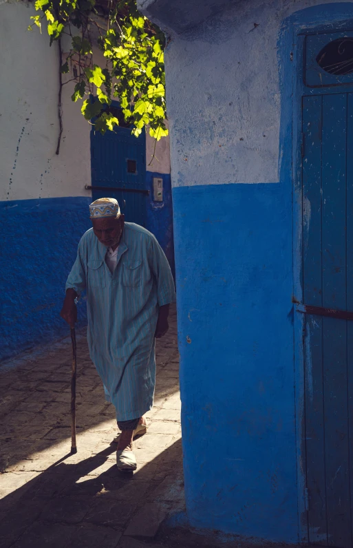 an older man walking down the street past blue houses