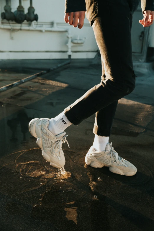 a closeup of a young man walking on pavement wearing white sneakers