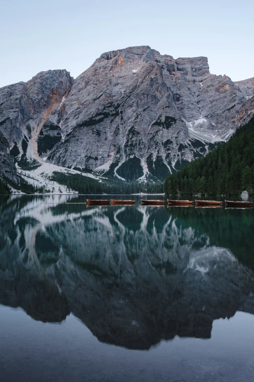 train on tracks next to lake surrounded by mountains