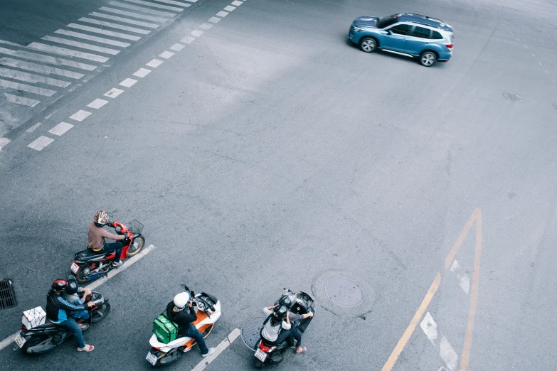 three motorbikes and several people in the middle of a road
